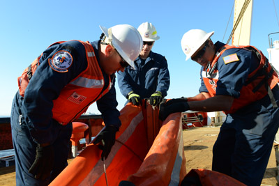 Chief Petty Officer Michael Presti, Petty Officer First Class James Maida, and Petty Officer Second Class Andrew Johnson assemble the foam filled boom for deployment onboard the CGC Edward Cornwallis.